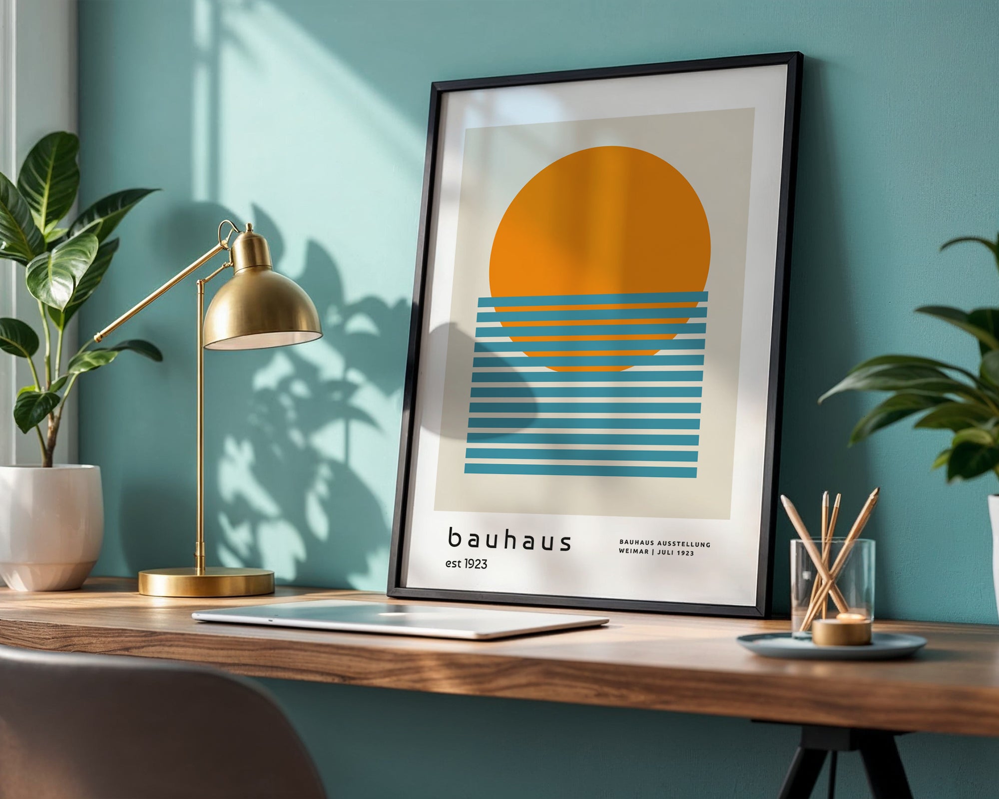 Framed Bauhaus poster on a desk with a lamp and plants against a teal wall.