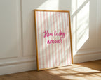 Framed print with 'How lucky are we?' text on a striped background, placed against a white wall.