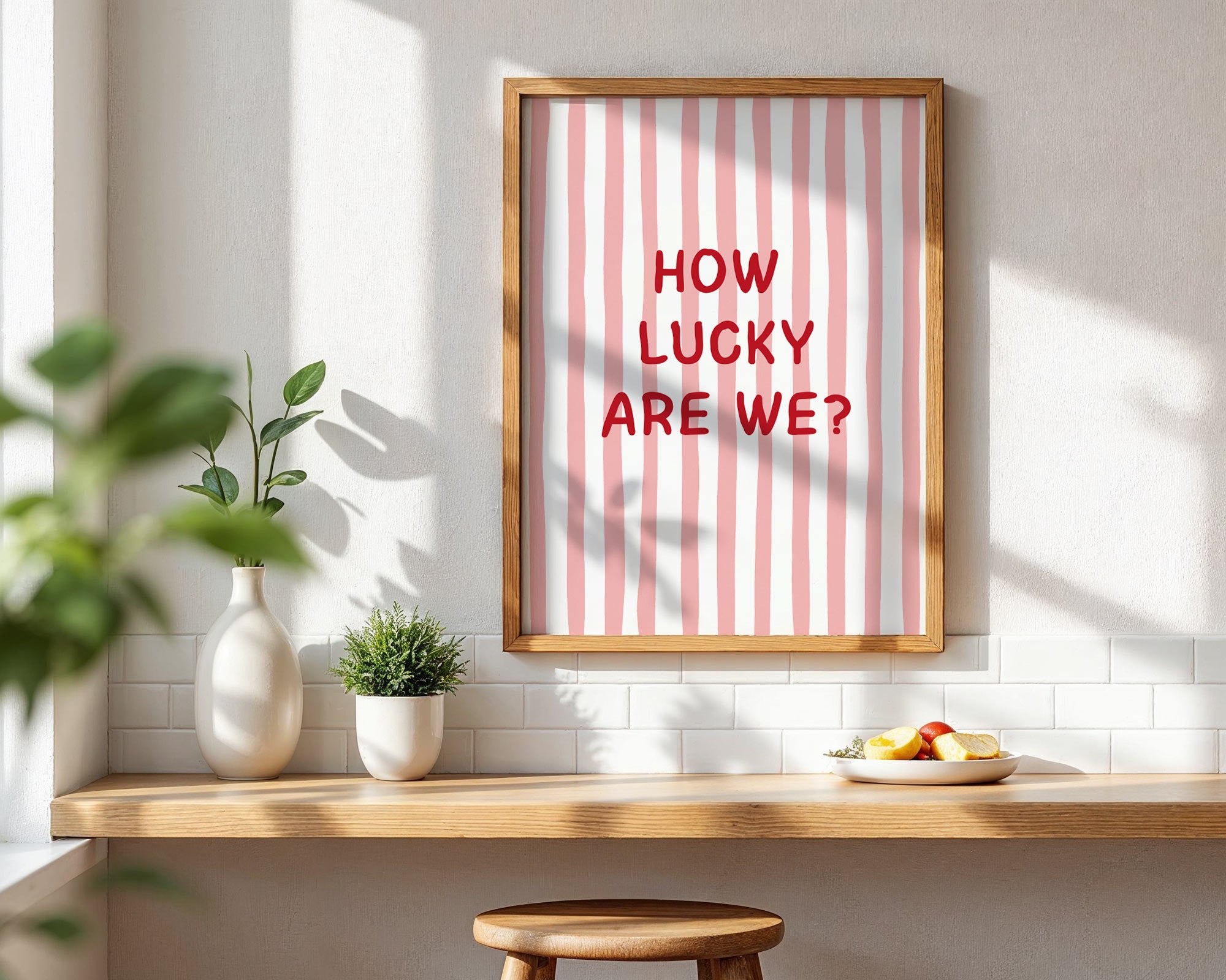 Framed poster with 'HOW LUCKY ARE WE?' text on a wall with a wooden shelf and plants.