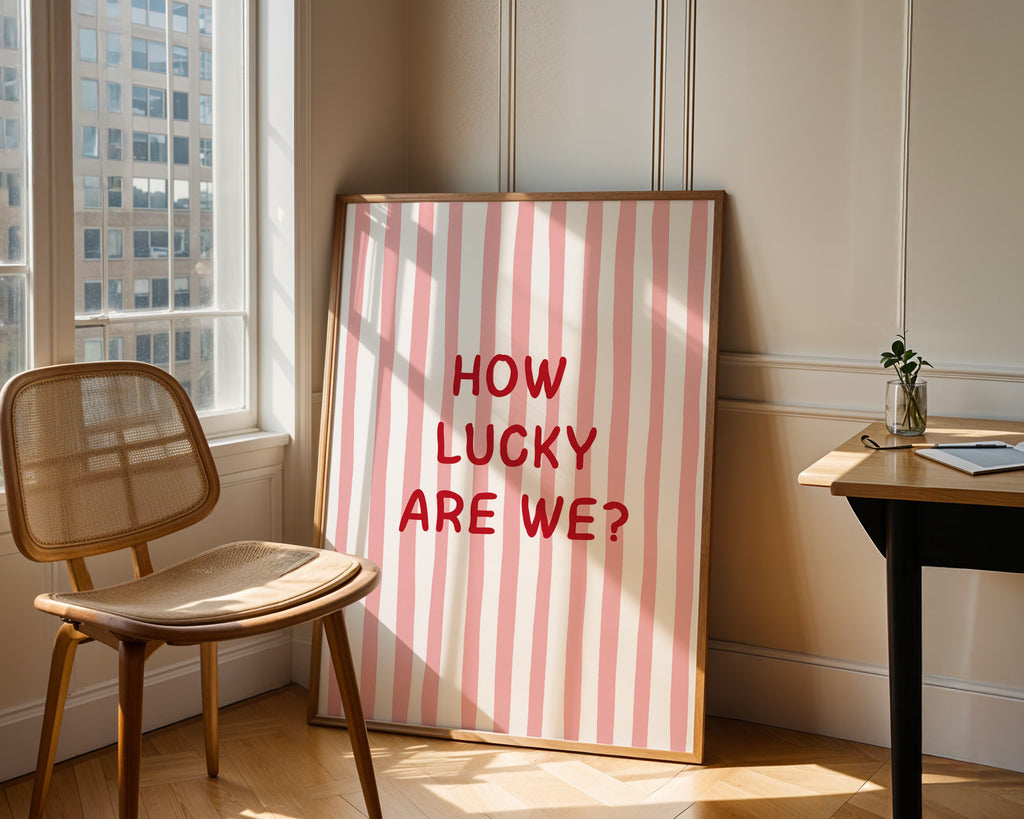 Framed picture with 'How Lucky Are We?' text in a room with a chair and table.