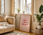 Living room with a beige sofa, plant, and a sign reading 'How Lucky Are We?'.
