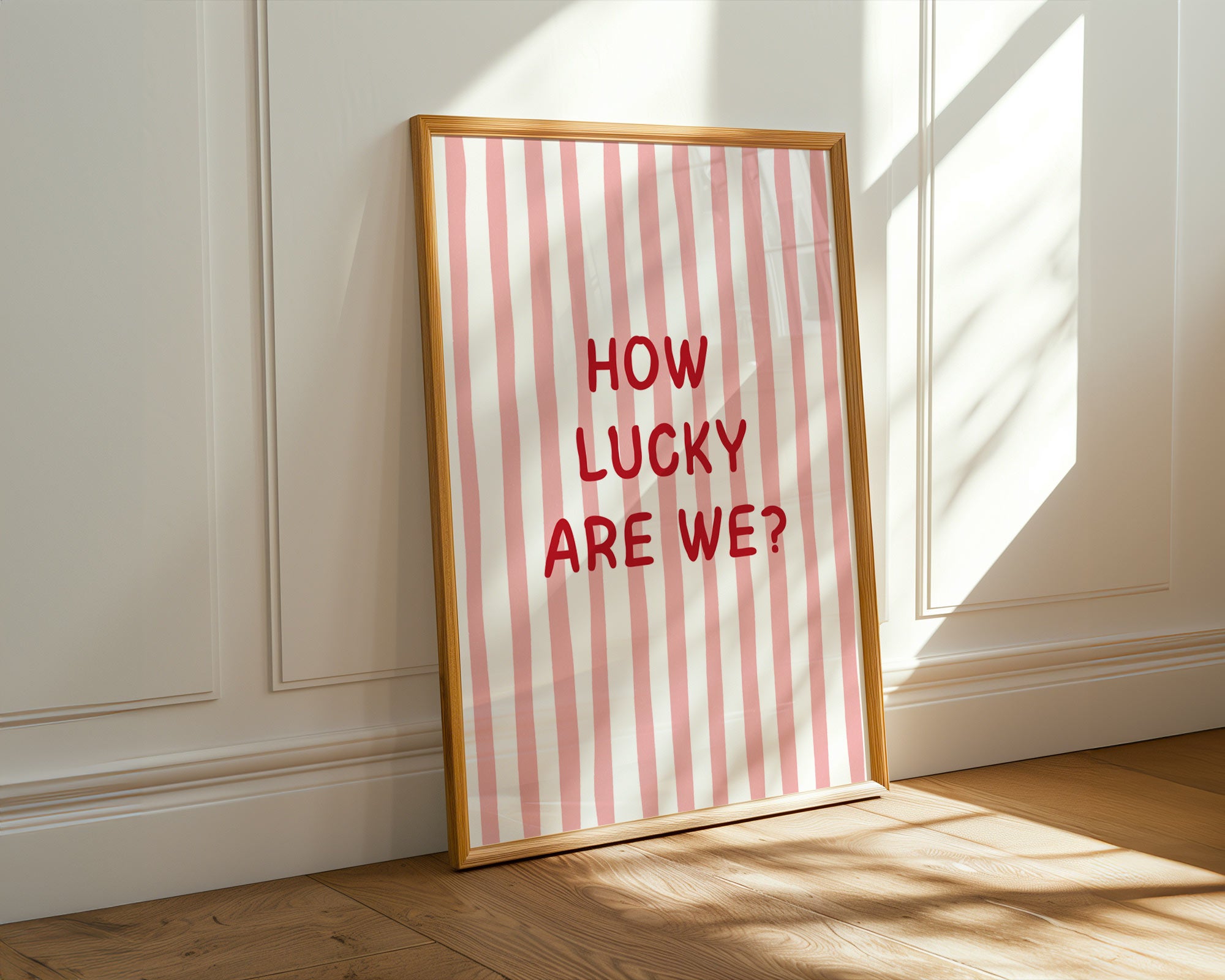 Framed print with 'How Lucky Are We?' text on a striped background, leaning against a wall.