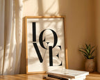 Framed 'LOVE' artwork on a shelf with books and a plant