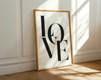Framed artwork with 'LOVE' on a wall with sunlight casting shadows