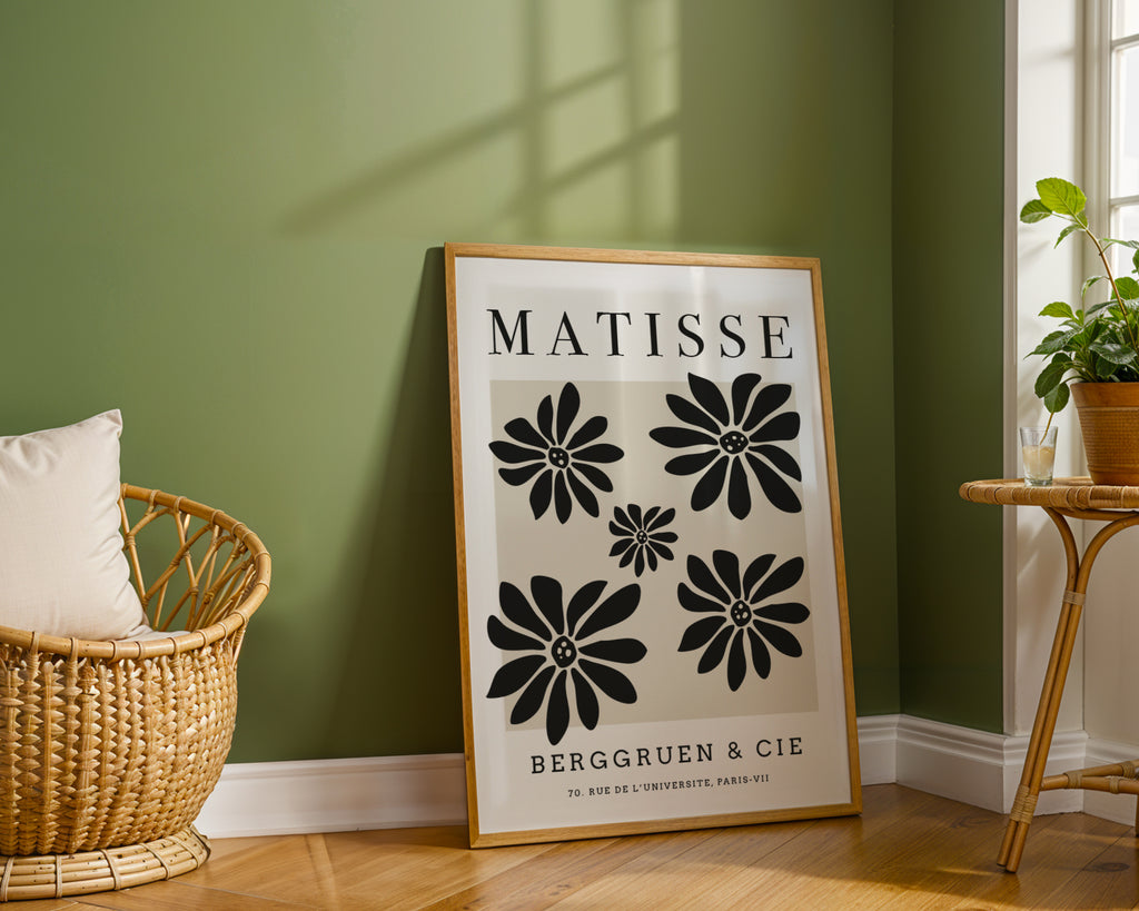 Framed Matisse poster on a green wall with a wicker chair and plant in the background