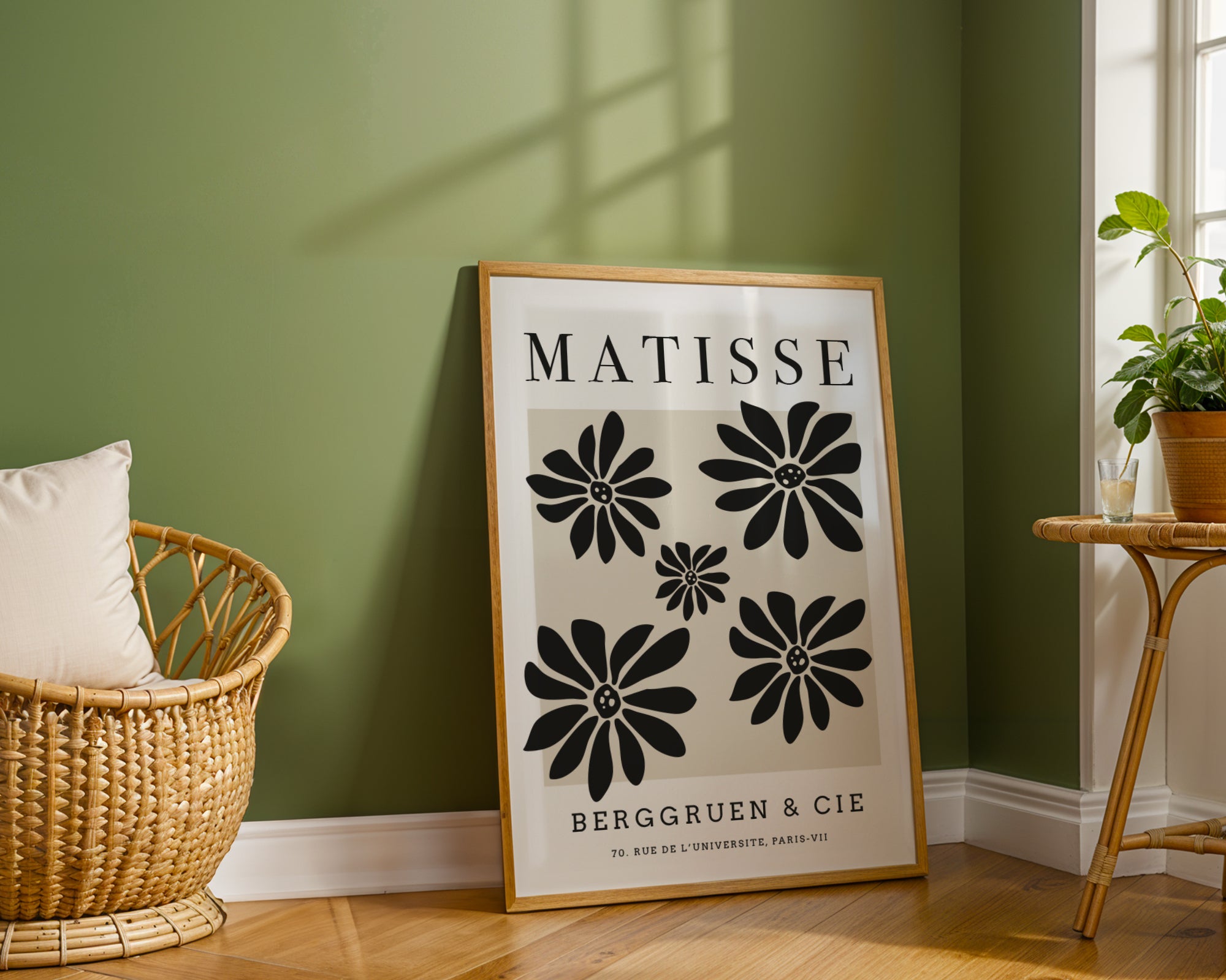 Framed Matisse poster on a green wall with a wicker chair and plant in the background