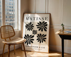 Framed Matisse poster in a room with a chair and table.