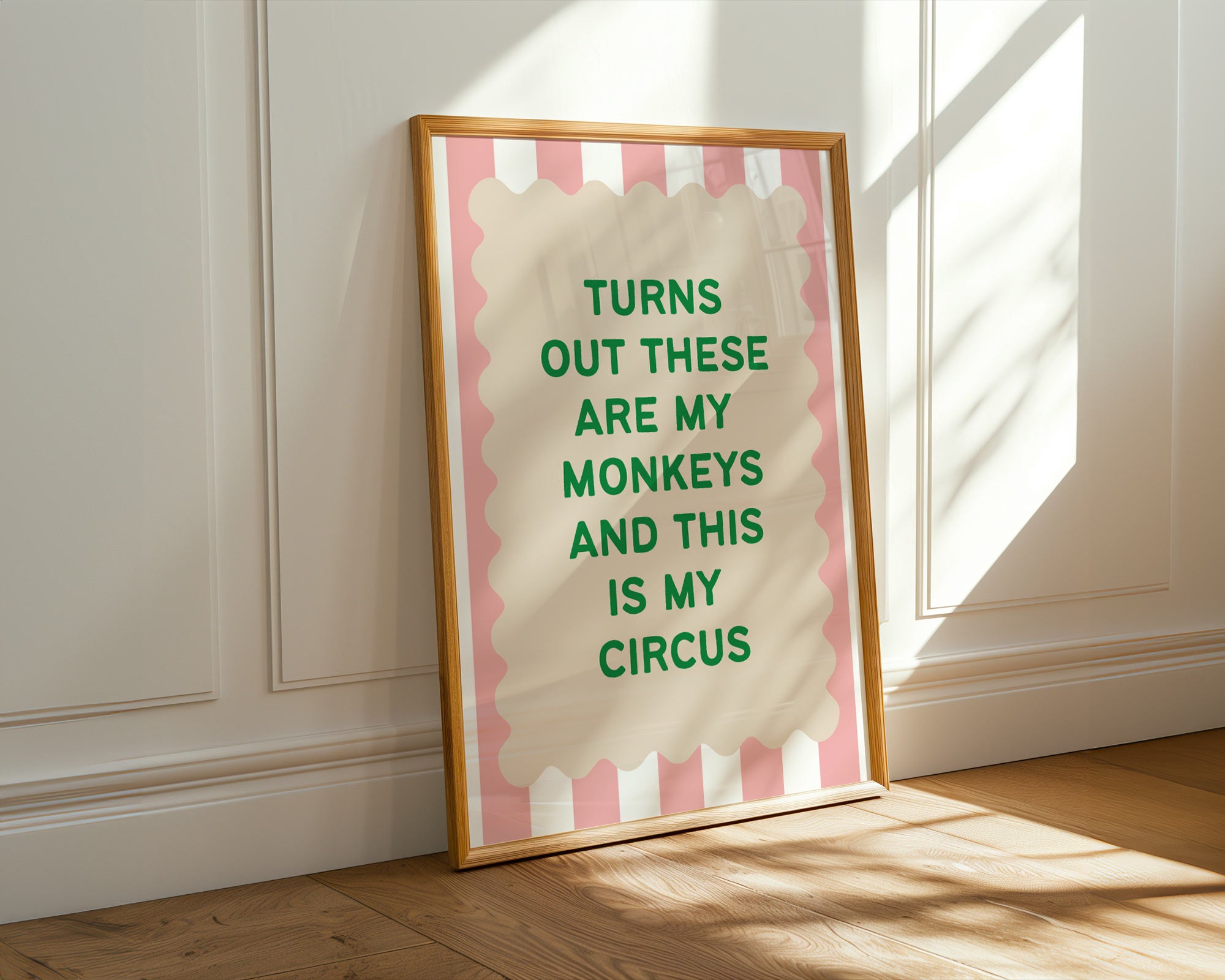 Framed print with text 'Turns out these are my monkeys and this is my circus' on a pink and white striped background, placed on a wooden floor.