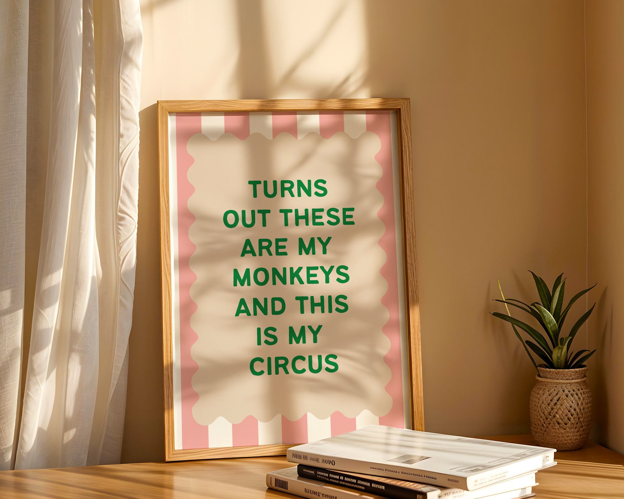 Framed print with text 'Turns out these are my monkeys and this is my circus' on a pink background, placed on a shelf with books and a plant.