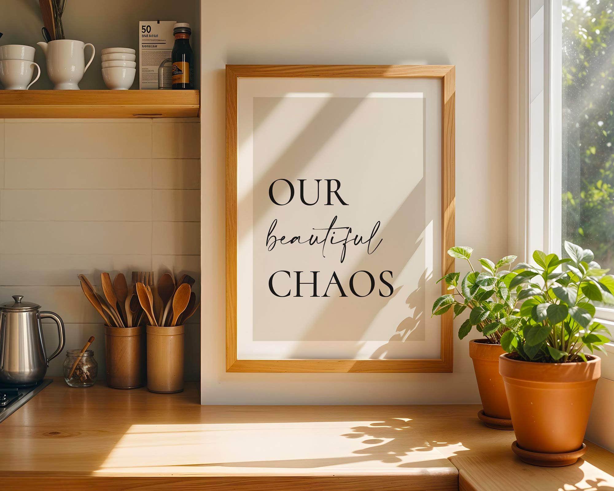 Framed print with 'Our beautiful chaos' text in a kitchen setting with plants and utensils.