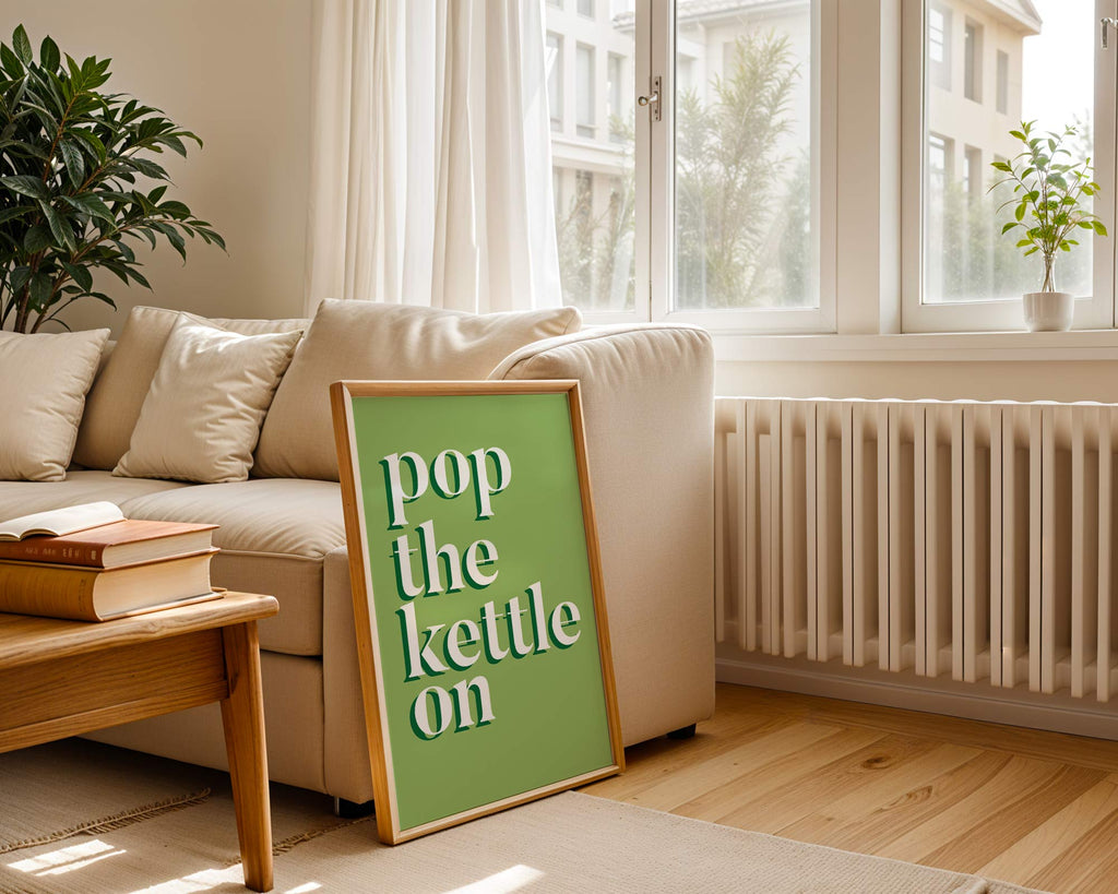 Living room with a 'pop the kettle on' sign, books, and a plant.