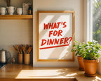 Kitchen counter with a framed sign asking 'What's for dinner?' and potted plants.