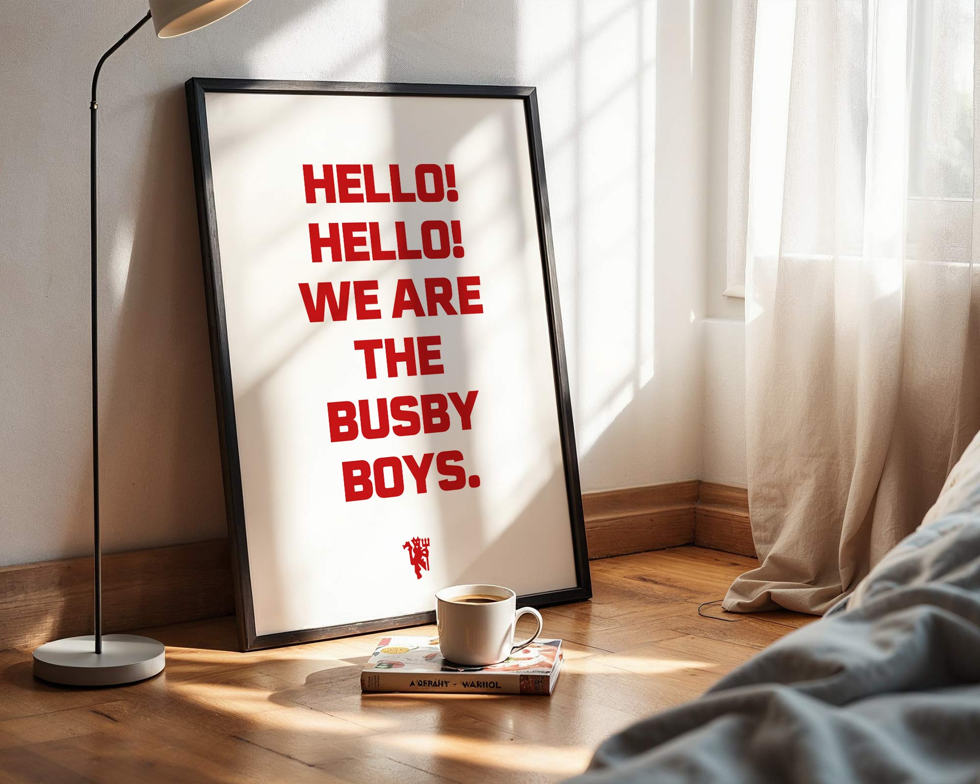 Framed poster with 'HELLO! HELLO! WE ARE THE BUSBY BOYS.' text in a room with a lamp and book.