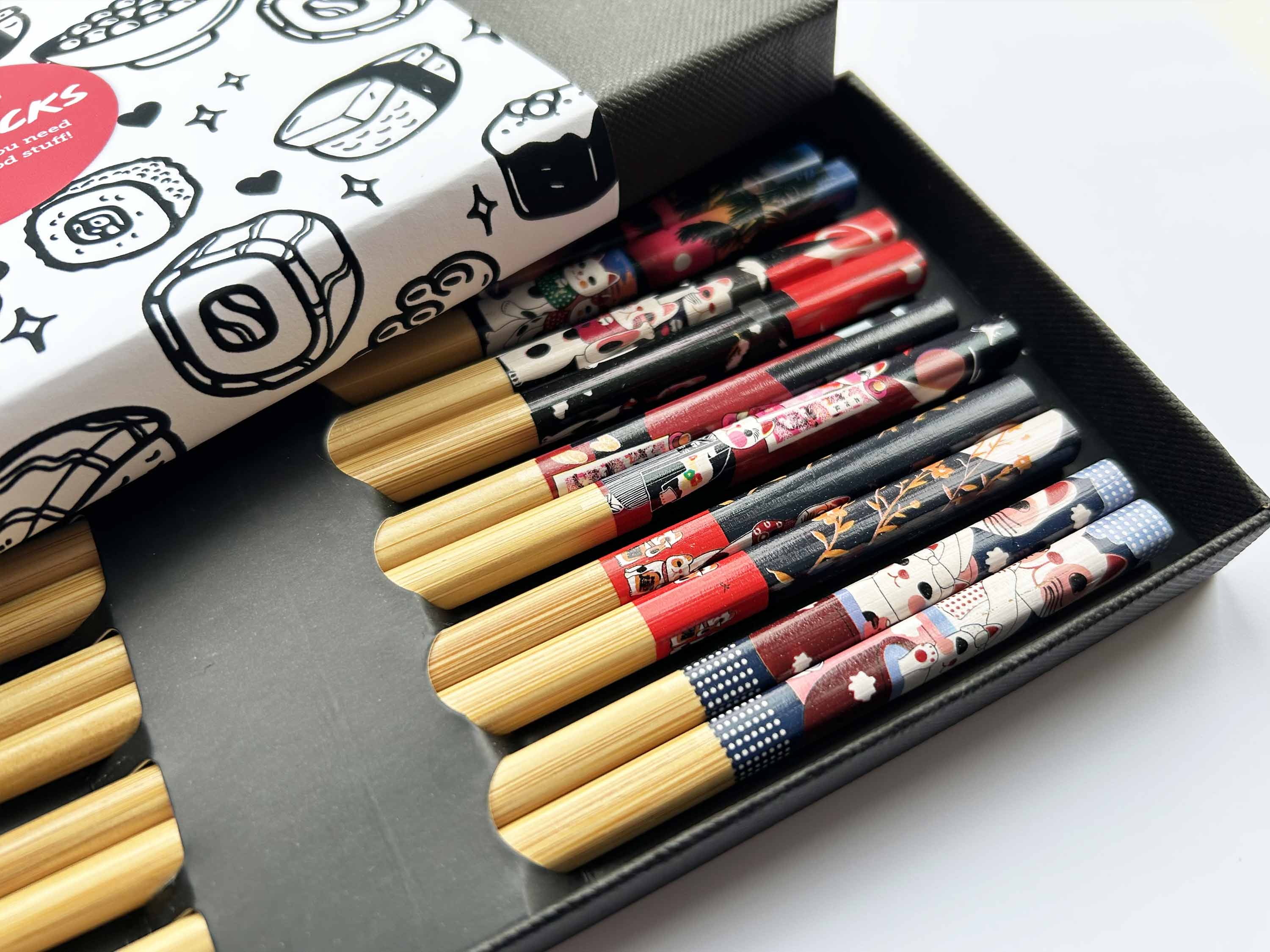 Set of decorative chopsticks in a black box with a branded box in the background