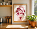 Framed print with 'You're my cup of tea' text in a kitchen setting with plants and cups.