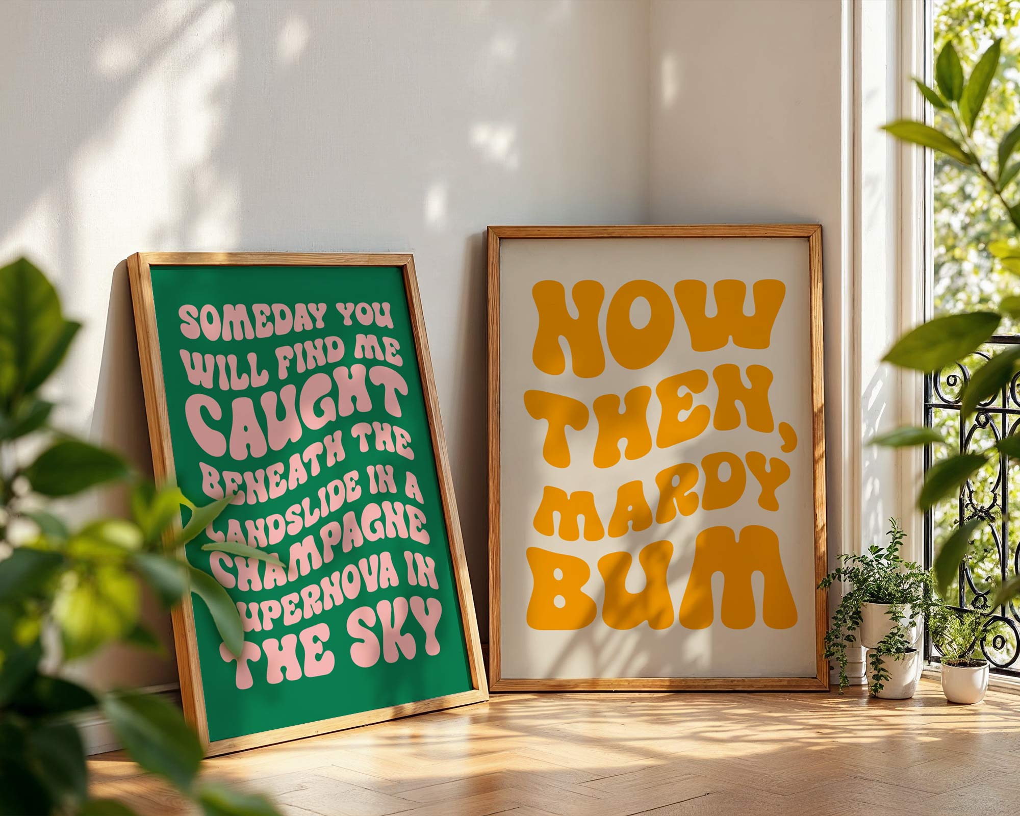 Two framed posters on a wall with decorative plants around