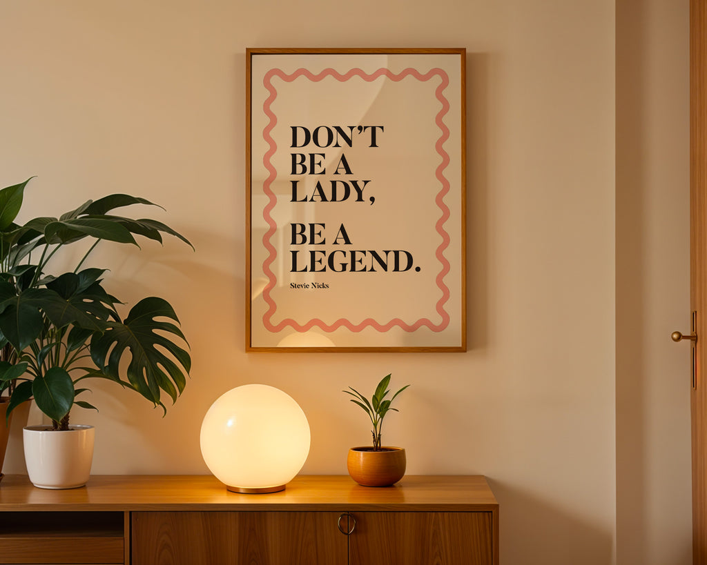 Framed quote 'Don't be a lady, be a legend' on a wall above a wooden cabinet with decorative items.