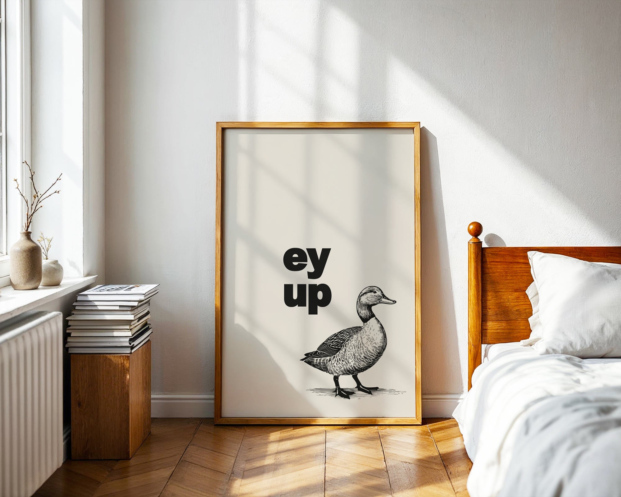 Framed artwork with a duck illustration and text in a bedroom setting