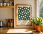 Framed Bauhaus poster on a kitchen wall with plants and kitchenware.