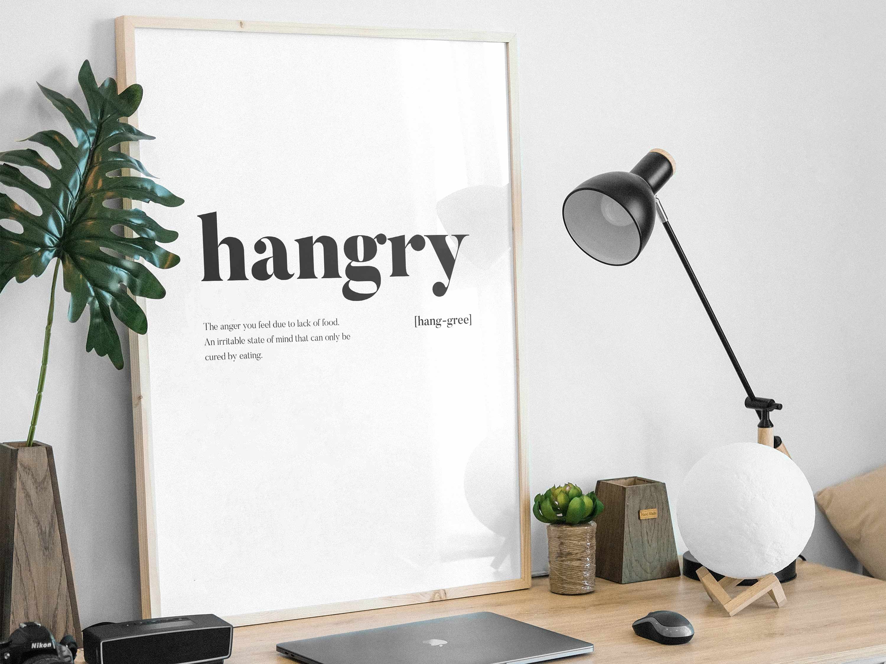 Modern office setup with 'hangry' poster, lamp, and plants on a desk.