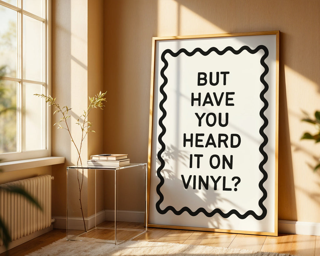 Framed poster with text 'BUT HAVE YOU HEARD IT ON VINYL?' in a room with a window and plant.