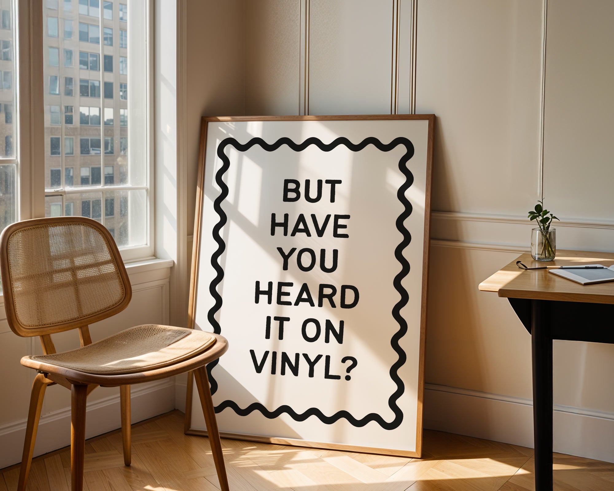 Framed poster with text 'BUT HAVE YOU HEARD IT ON VINYL?' in a room with a chair and table.