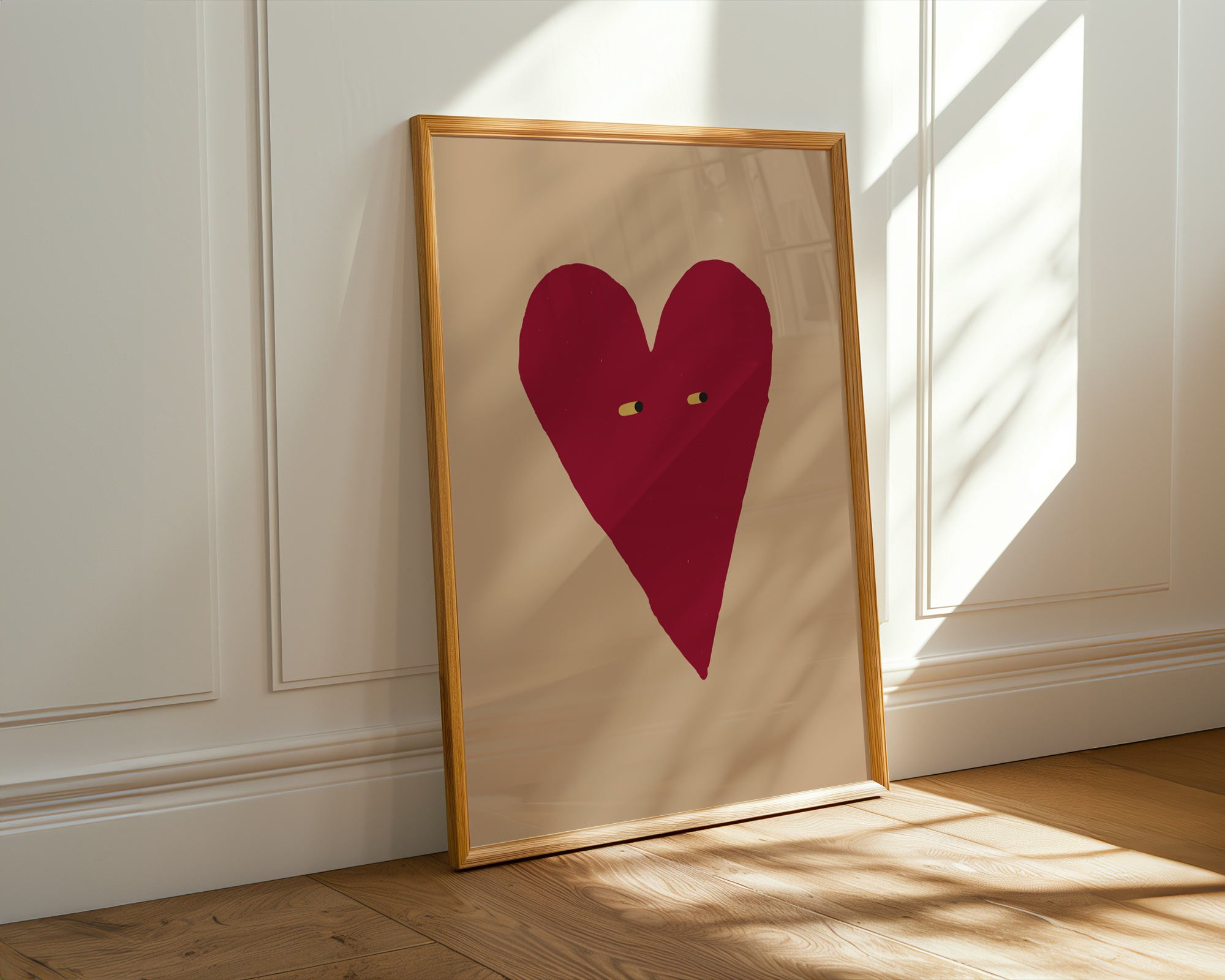 Framed artwork with a red heart on beige paper against a white wall.