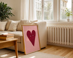 Heart-shaped picture on a table in a living room with a couch and window in the background