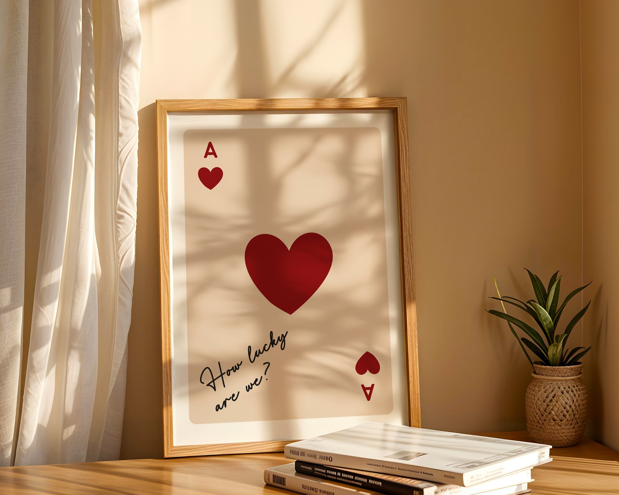 Framed artwork with red hearts and text on a shelf with books and a plant.