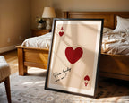 Framed card with hearts and text in a bedroom setting