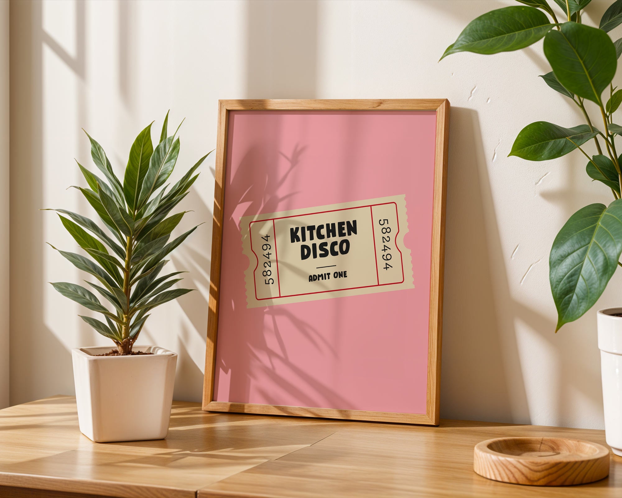 Framed 'Kitchen Disco' sign on a wooden surface with plants