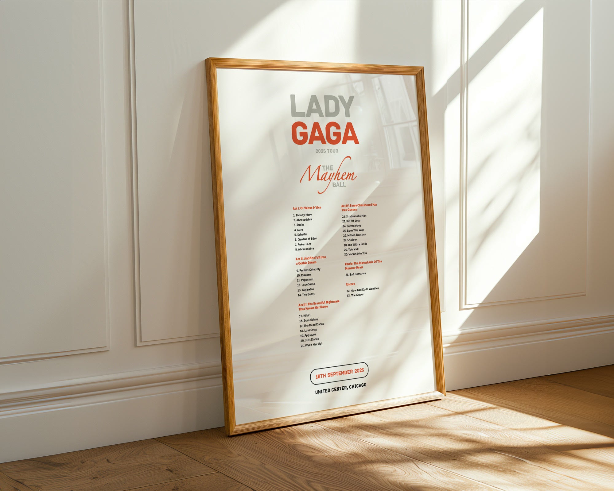 Framed poster of Lady Gaga's album 'Majik' on a wooden floor with sunlight casting shadows.