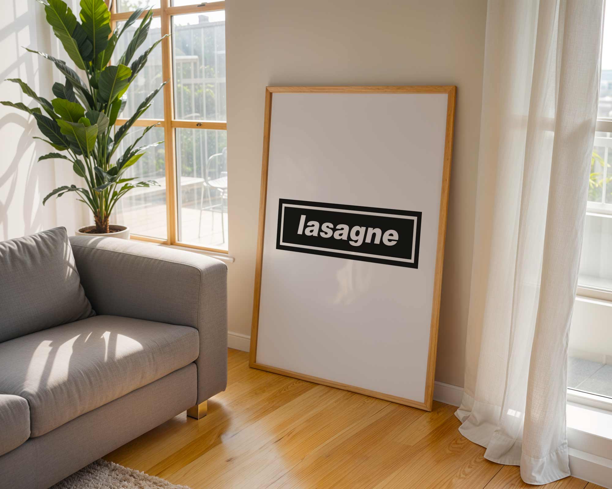 Living room with a gray sofa, framed picture of lasagne, and large window.