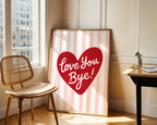 Framed artwork with a red heart and 'Love You Bye!' text in a room with a chair and window.