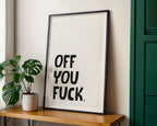 Framed artwork with text on a wall next to a plant