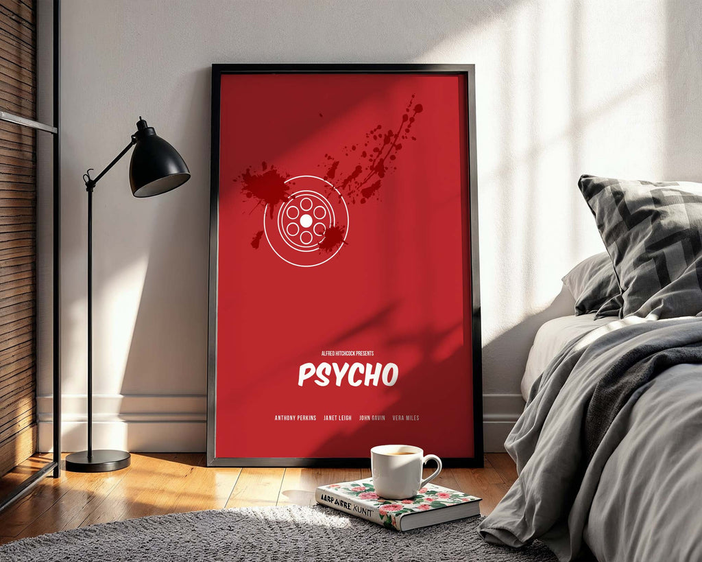 Framed 'Psycho' movie poster in a bedroom setting with a cup and book on a nightstand.