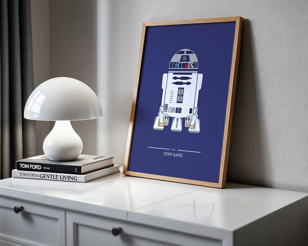 Framed poster of R2-D2 from Star Wars on a shelf with a lamp and books.
