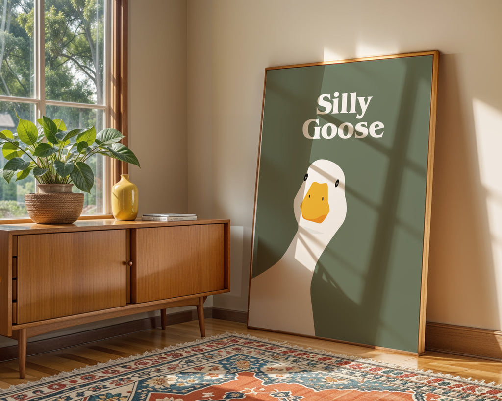 Framed artwork with 'Silly Goose' text in a room with a wooden cabinet and plants.