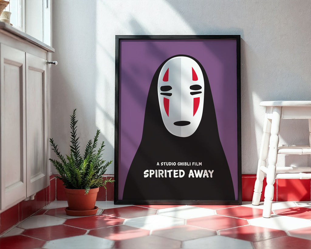 Framed 'Spirited Away' poster with a character's face on a purple background in a room with a plant and table.