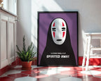 Framed 'Spirited Away' poster with a character's face on a purple background in a room with a plant and table.