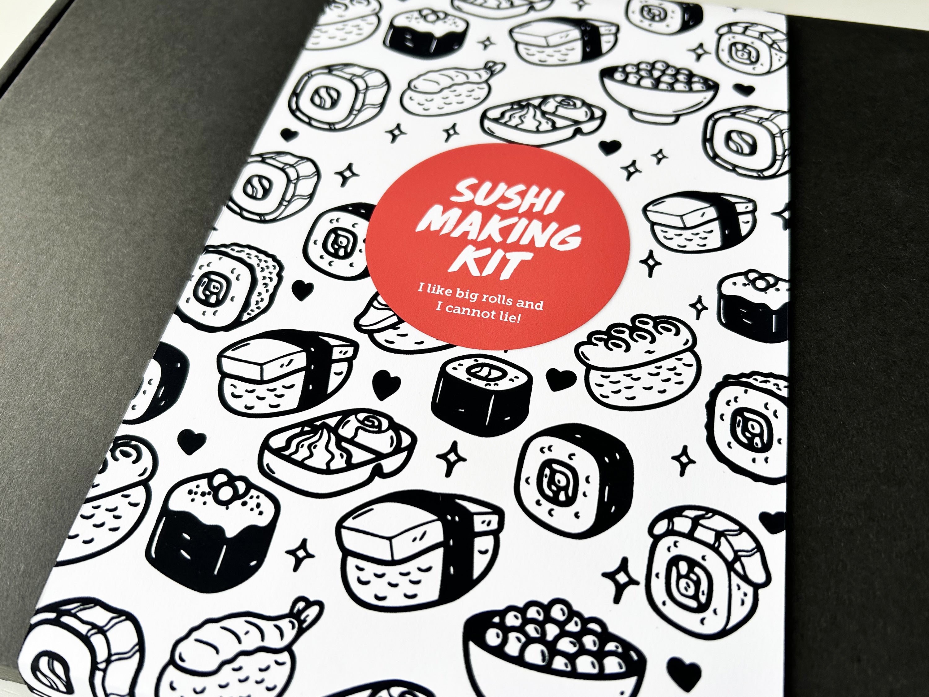Sushi making kit packaging with black and white sushi illustrations and a red label.