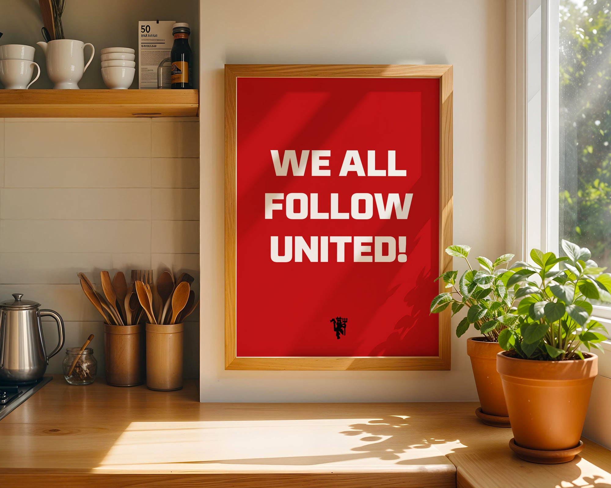 Red poster with 'WE ALL FOLLOW UNITED!' text in a wooden frame on a kitchen wall.