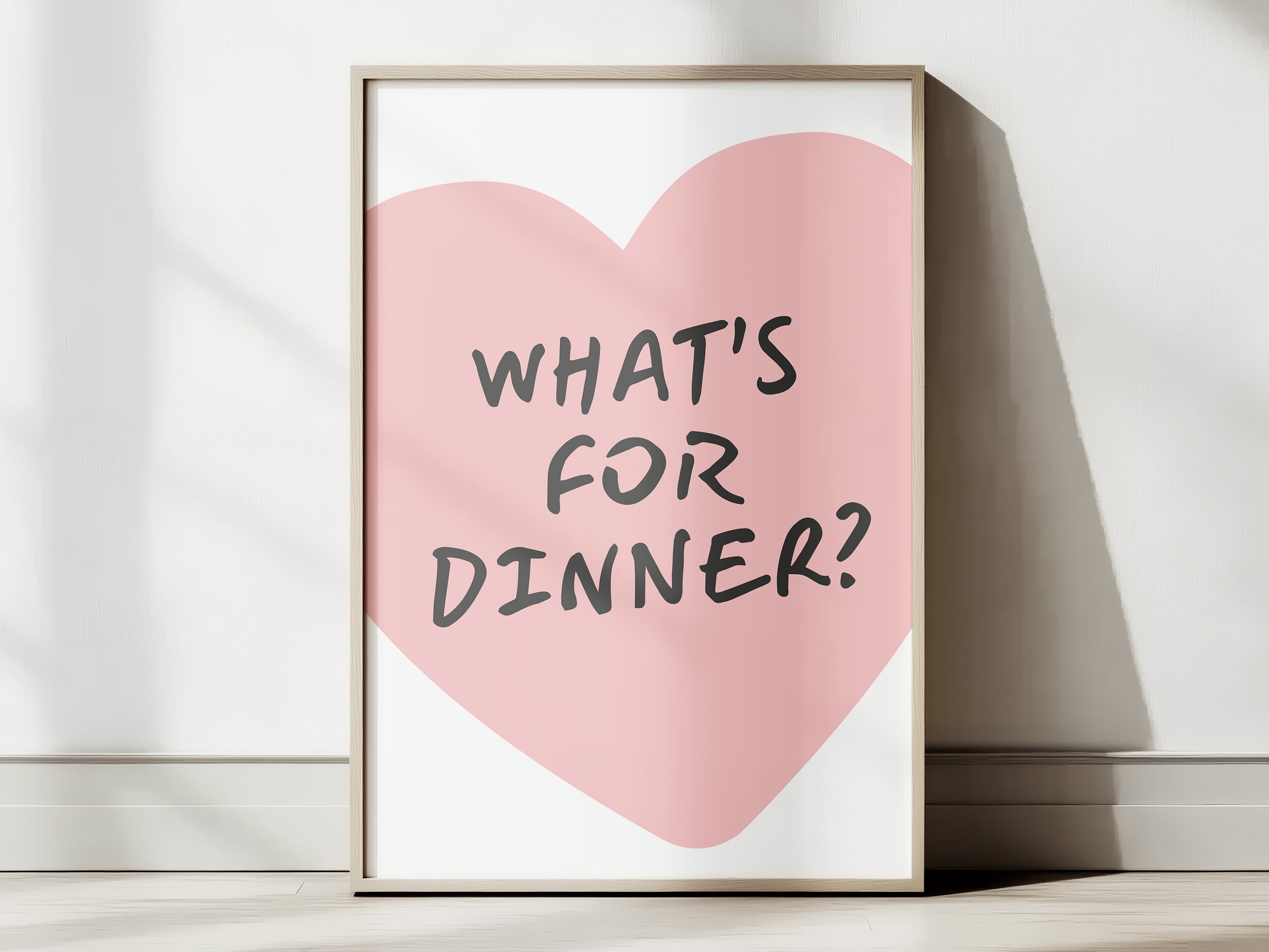 Framed print with a pink heart and 'What's for dinner?' text on a white surface.