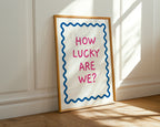 Framed poster with 'How Lucky Are We?' text on a wall.