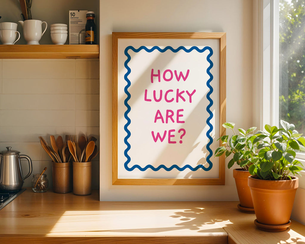 Framed poster with 'How Lucky Are We?' text in a kitchen setting